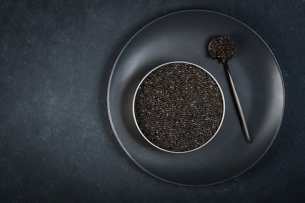 Bol de caviar noir de poisson d'esturgeon sur une surface bleu foncé.Vue d'en haut