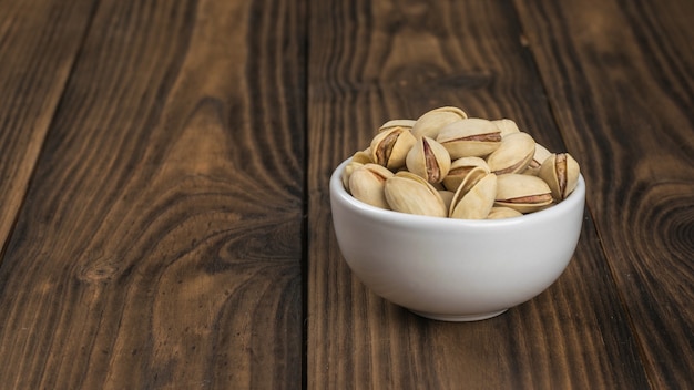 Bol en céramique aux pistaches sur une table en bois