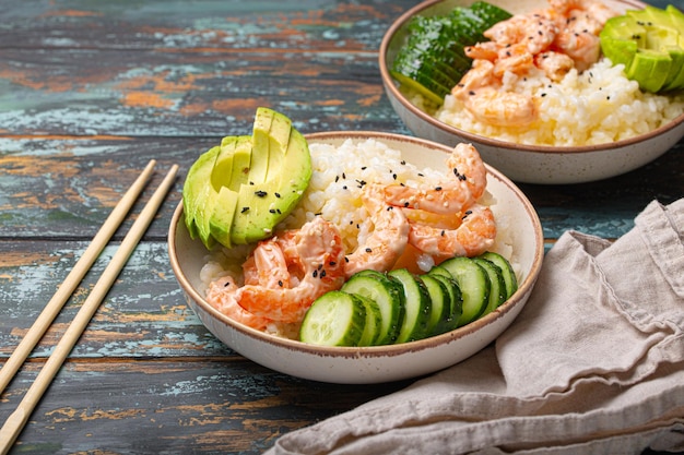 Photo un bol en céramique blanche avec du riz, des crevettes, des légumes et de l'avocat.