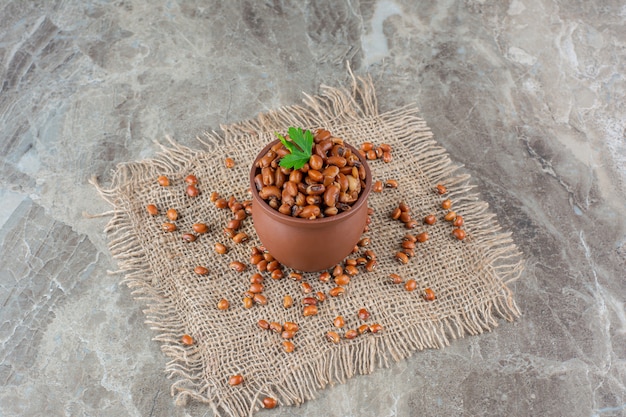 Bol en céramique de haricots bouillis avec de la toile de jute sur une surface en marbre.