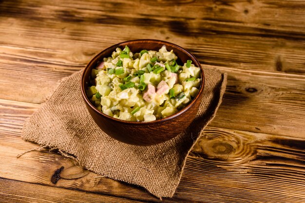 Bol en céramique avec salade traditionnelle russe olivier sur table en bois