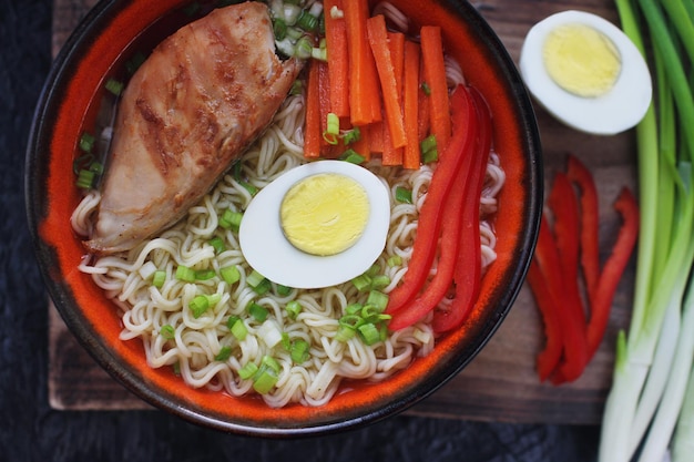 Bol en céramique de soupe de ramen asiatique traditionnelle avec nouilles poulet à l'oignon de printemps et œuf tranché