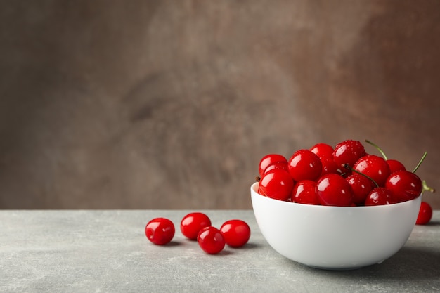 Bol avec cerise rouge sur table grise, espace pour le texte