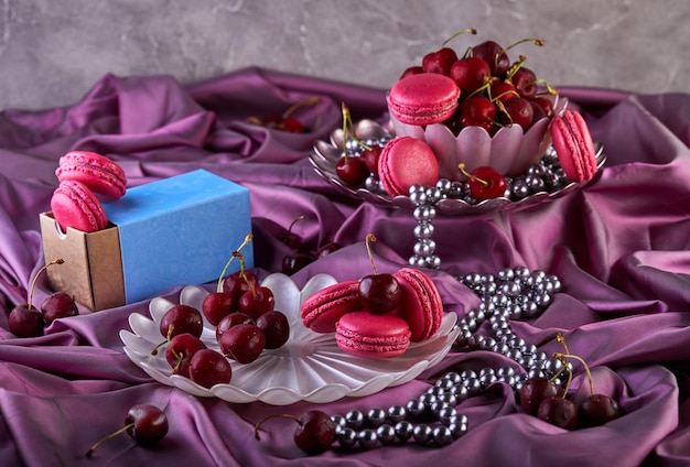 un bol de cerises à côté d'un bol de macarons roses