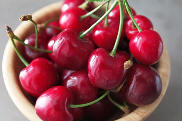 Bol avec des cerises mûres fraîches sur fond gris