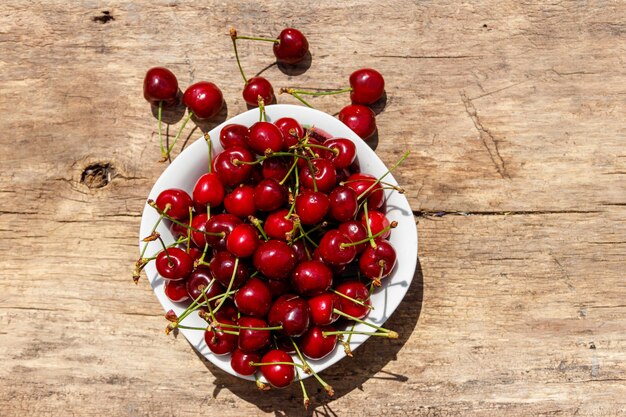 Bol avec des cerises mûres fraîches sur une table en bois rustique. Vue de dessus