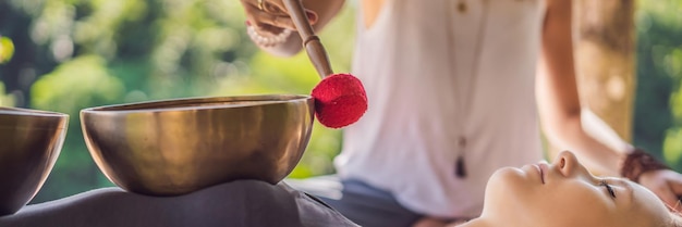 Bol chantant en cuivre bouddha népal format long bannière au salon spa jeune belle femme faisant un massage