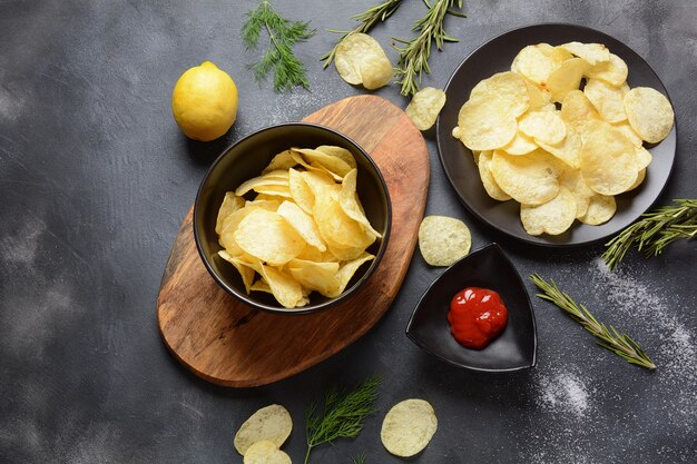 Bol de chips maison croustillantes servies avec ketchup, romarin, herbes et épices