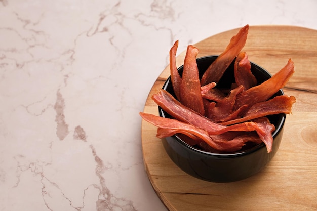 Un bol de chips de poulet séchées sur un fond de marbre clair