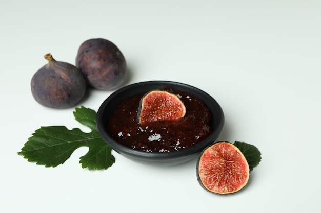 Bol avec confiture de figues et ingrédients sur fond blanc