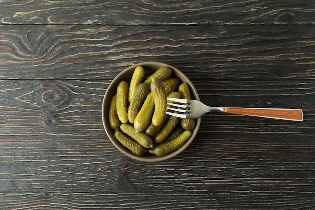 Bol de cornichons et fourchette sur fond de bois