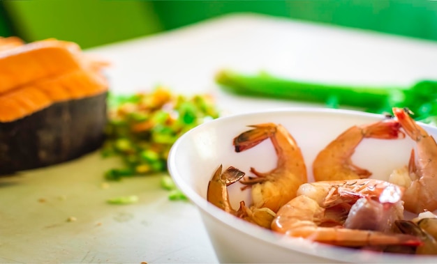 Bol de crevettes crues sur la table avec des légumes hors focus background Crevettes crues sur la table avec des légumes hors focus background