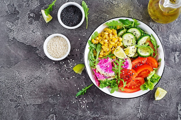 Bol de crudités fraîches - concombre, tomate, radis pastèque, laitue, roquette et maïs.