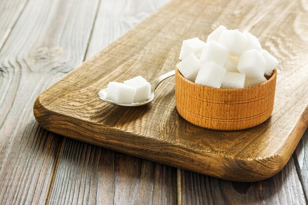 Bol et cuillère pleine de sucre sur fond de bois