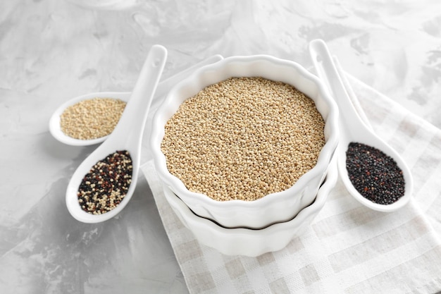 Bol et cuillères avec différentes graines de quinoa sur table