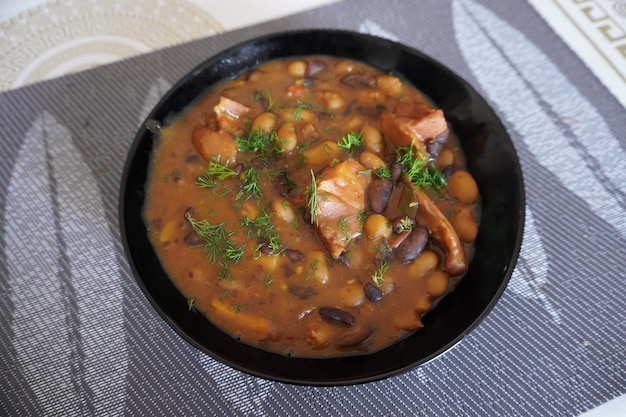 Bol avec cuisse de porc fumé et ragoût de haricots sur table