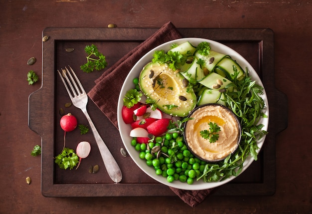 Bol à déjeuner végétalien sain avec radis pois hummus concombre avocat