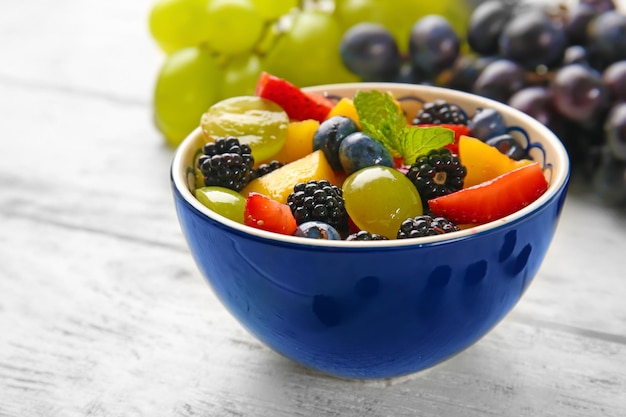 Bol avec une délicieuse salade de fruits sur table en bois