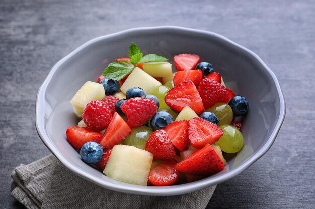 Bol avec une délicieuse salade de fruits sur une table grunge