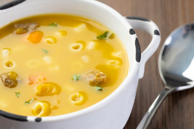 Photo un bol de délicieuse soupe brésilienne avec du bœuf, des légumes, des nouilles, des carottes et des pommes de terre.