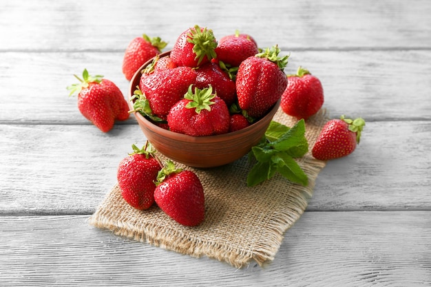 Bol avec de délicieuses fraises fraîches sur une table en bois