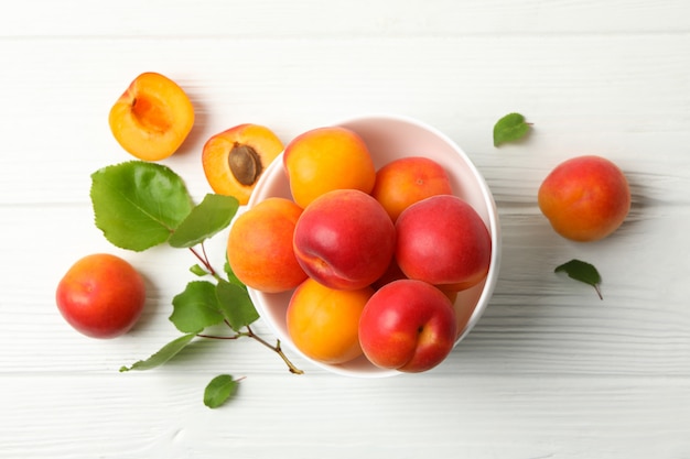 Bol avec de délicieux abricots sur bois blanc