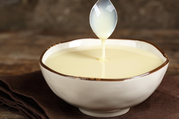 Bol avec du lait concentré sur une serviette sur fond de bois