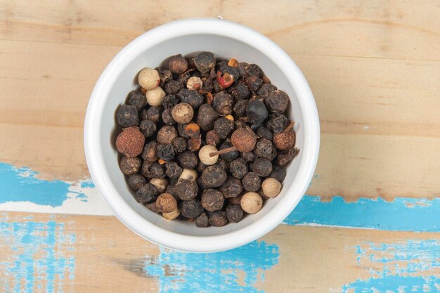 Bol avec du poivre noir moulu sur une table en bois rustique bleue