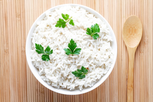 Bol avec du riz blanc bouilli avec du persil frais vert pour un délicieux déjeuner sain. Céréales et plats.