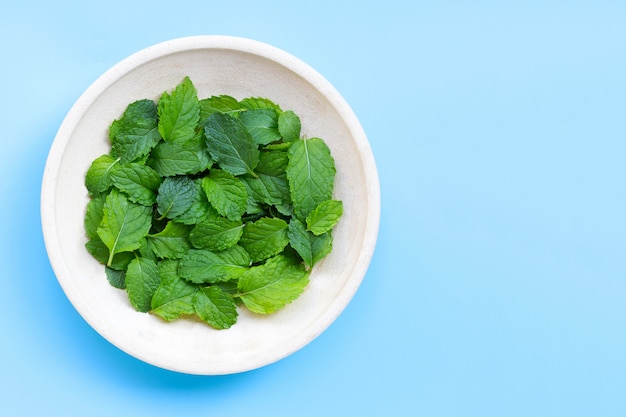 Bol De Feuilles De Menthe Sur Table Bleue.