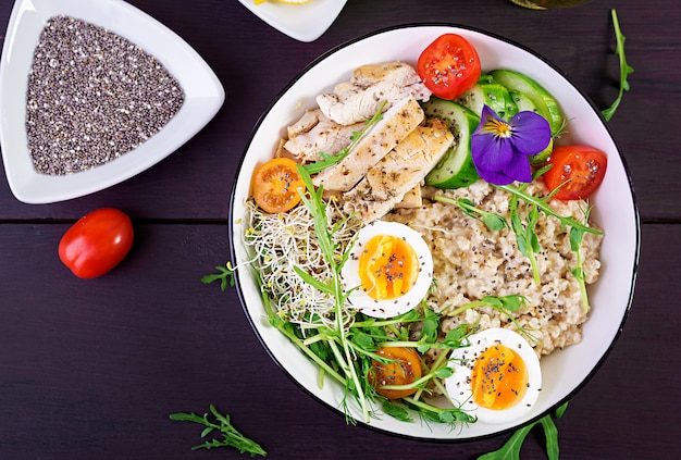 Bol de flocons d'avoine, filet de poulet, tomate, laitue, micro-légumes et œuf à la coque