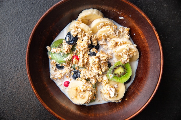 bol de flocons d'avoine fruits banane kiwi baies bleuets prêt à manger collation repas sur la table