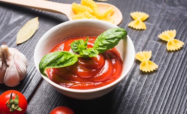 Bol frais de sauce tomate avec feuille de basilic et ingrédients