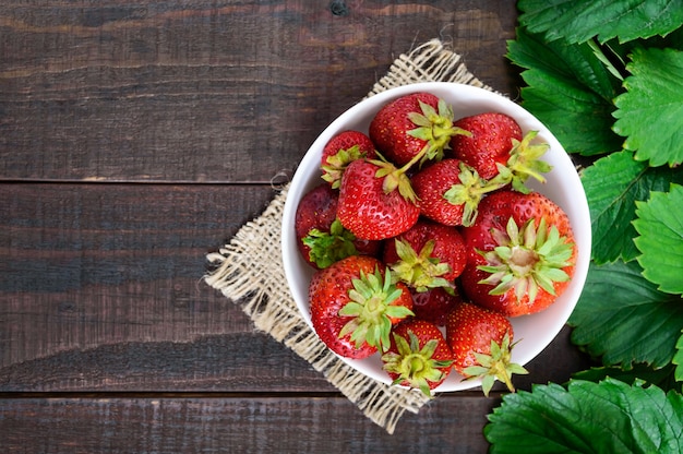 Bol de fraise mûre et de feuilles vertes