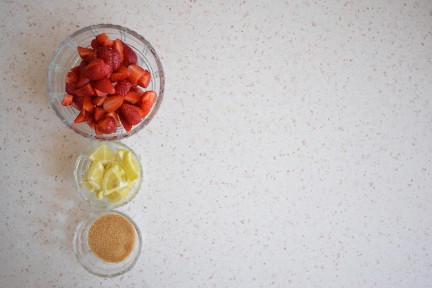 Un bol de fraises un citron et de la cassonade Les ingrédients d'une limonade