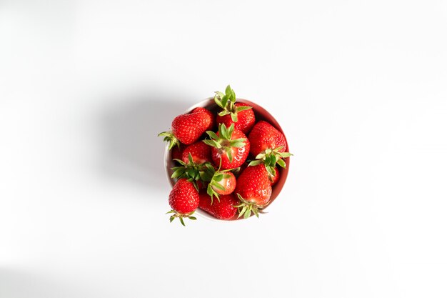 Bol avec des fraises fraîches sur fond blanc. Composition d'été