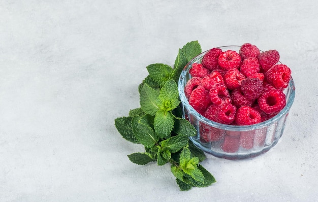 Photo bol de framboises juteuses fraîches sur fond gris