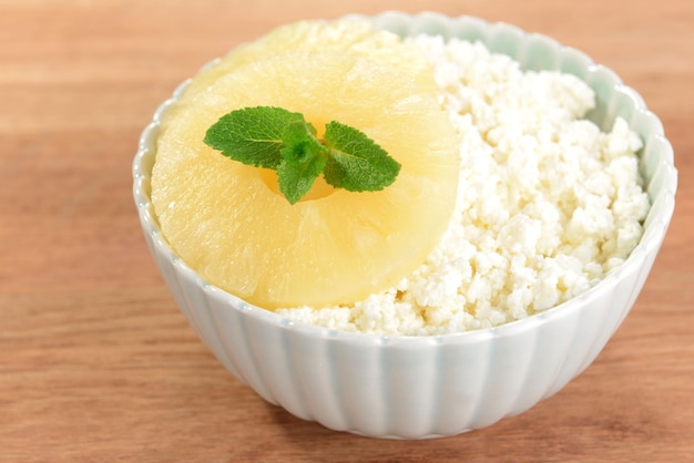 Bol de fromage cottage savoureux à l'ananas sur table en bois