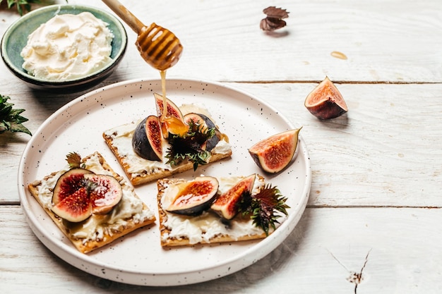 Bol de fromage à la crème Canape ou crostini Fromage à la crème aux figues et sandwichs au miel Fond de recette alimentaire Gros plan