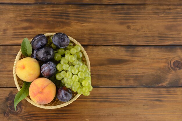 Un bol de fruits d&#39;été mûrs et savoureux sur la table en bois marron.