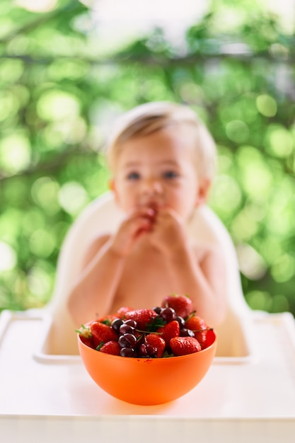 Bol de fruits sur la table devant un enfant qui mange