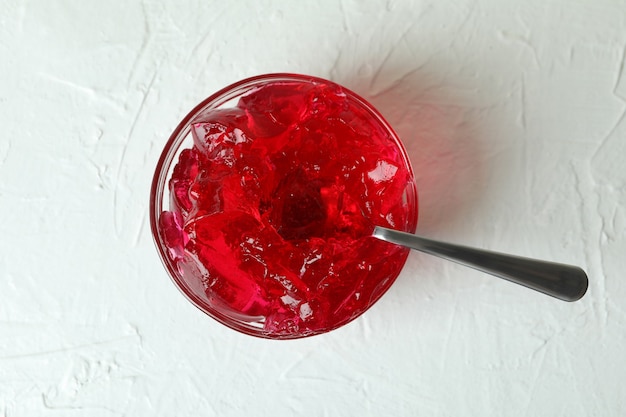 Bol de gelée de fraise avec cuillère sur table texturée blanche