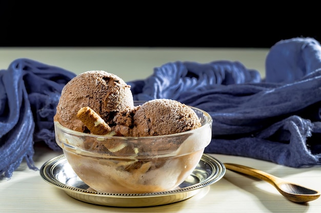 Un bol de glace au chocolat avec une serviette bleue derrière.