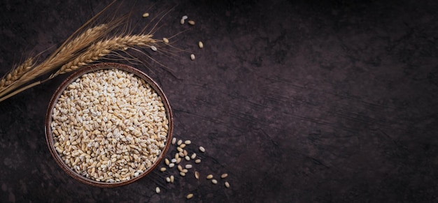 Bol de grains de céréales d'orge perlé cassés séchés crus