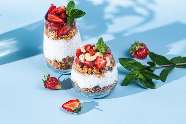 Un bol de granola aux fraises et fraises sur fond bleu.