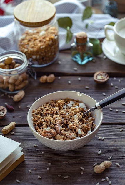 Bol avec granola fait maison et noix de cuillère sur fond de table en bois marron