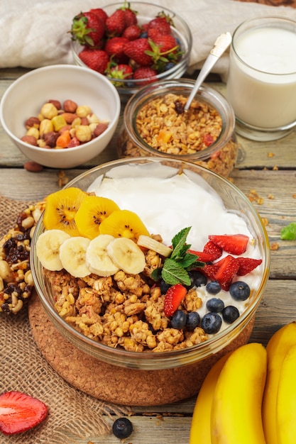 Photo bol de granola maison avec du yaourt et des baies fraîches sur bois