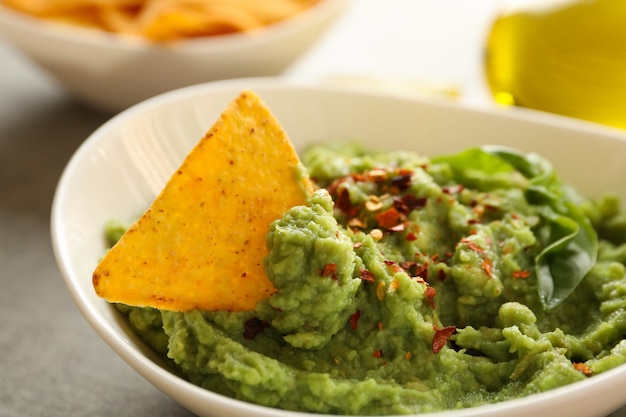 Bol avec guacamole, épices, basilic et chips, gros plan