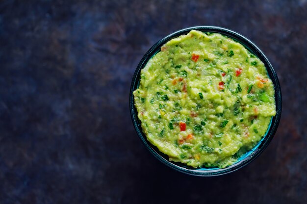 Bol de guacamole sur fond sombre. Sauce trempette mexicaine traditionnelle guacamole. Cuisine mexicaine traditionnelle. Espace de copie. Vue de dessus