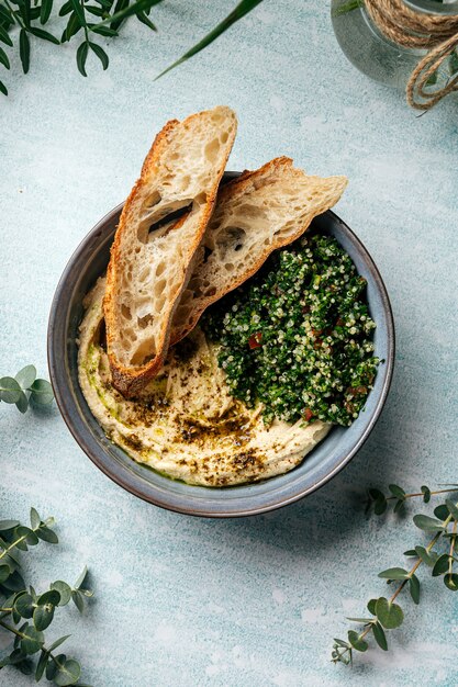 Bol d'houmous avec salade de taboulé et toasts sur le fond bleu